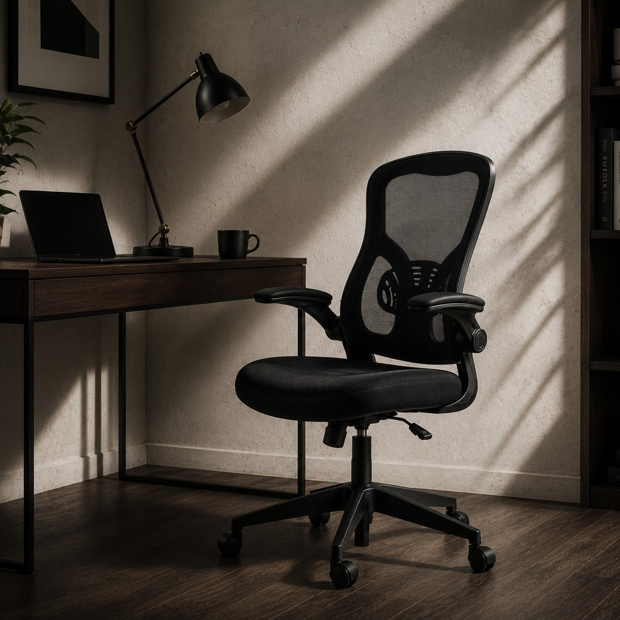 ARTIC black mesh office chair with flip-up armrests at dark wood desk with lamp in moody home office