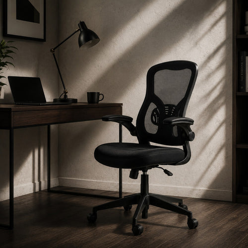ARTIC black mesh office chair with flip-up armrests at dark wood desk with lamp in moody home office